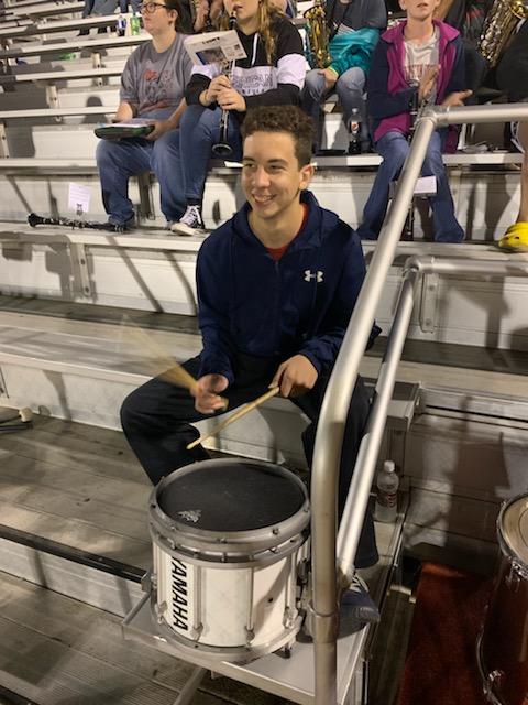 A student from the school playing a drum in the school's football field.
