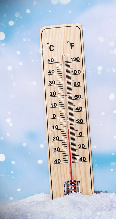 An image of a thermostat surrounded with snow.