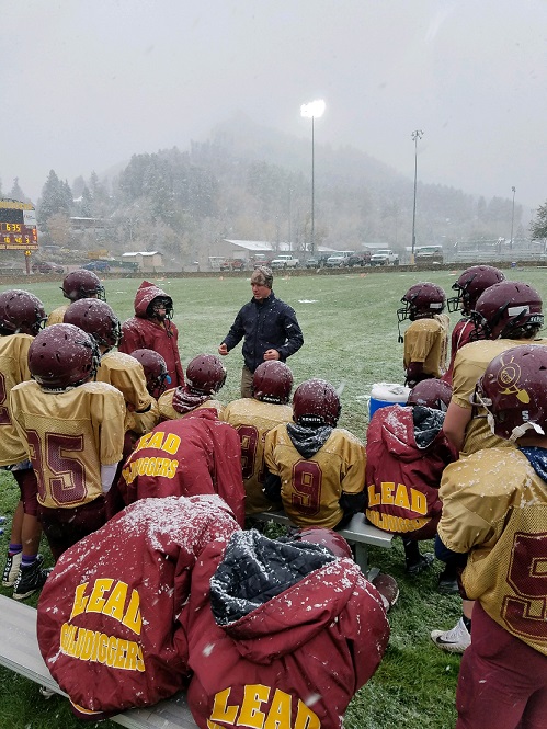 A photo of the football team paying attention to their coach while snowing.