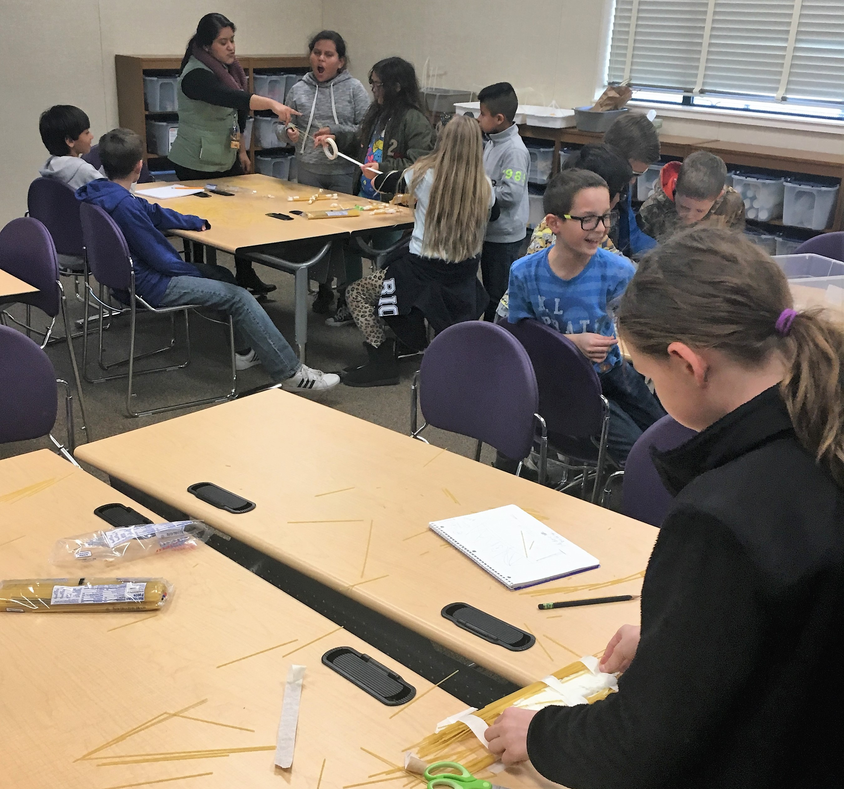 The students all trying to build a bridge with pieces of raw pasta