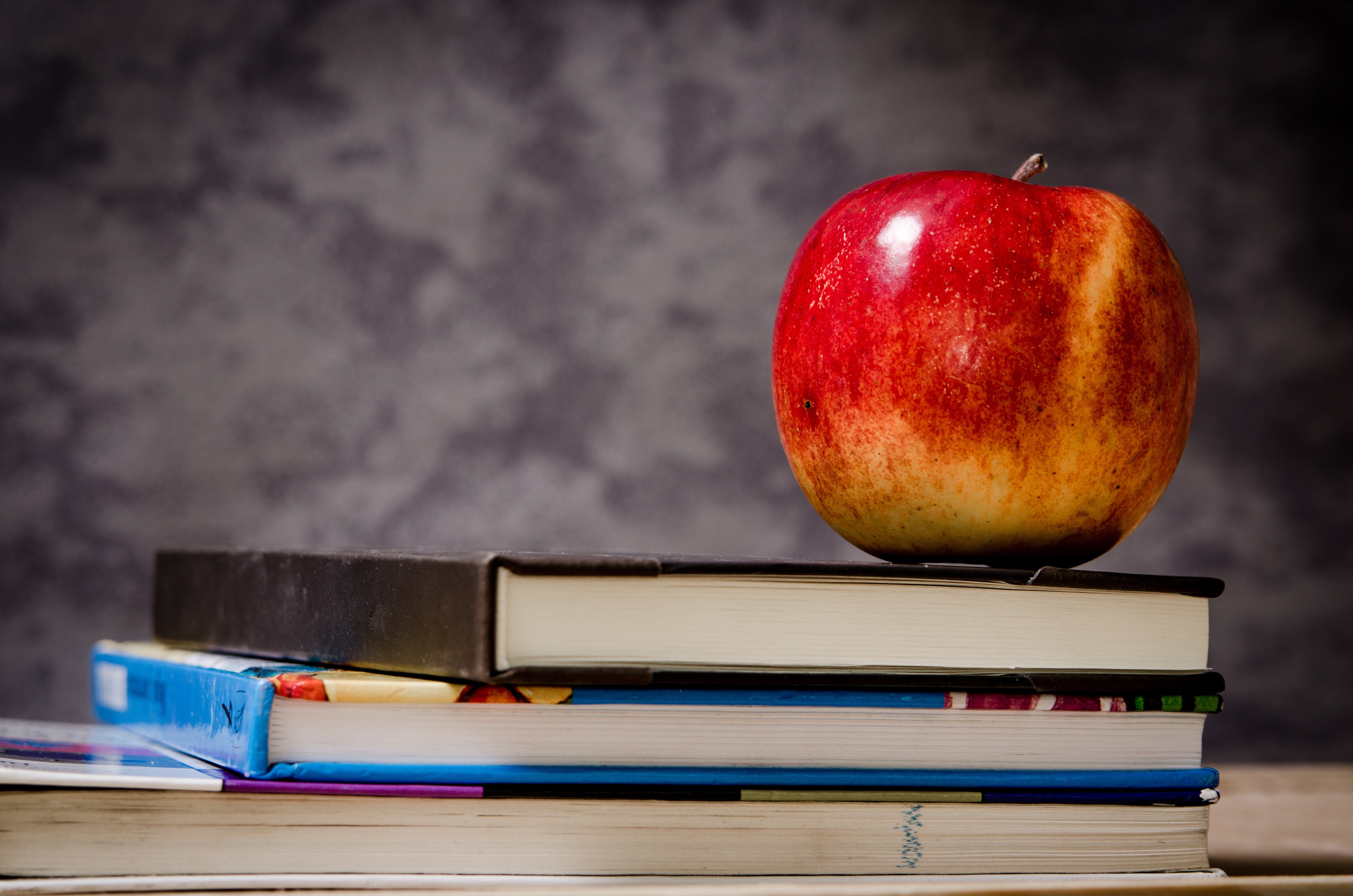 A photo of some books and an apple.