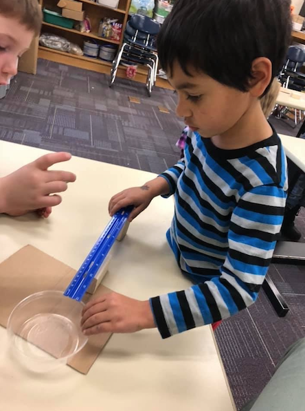 Two little kids working on an experiment inside the classroom