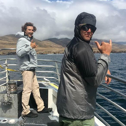 Two professors posing for the camera, the two of them standing on a sailing boat