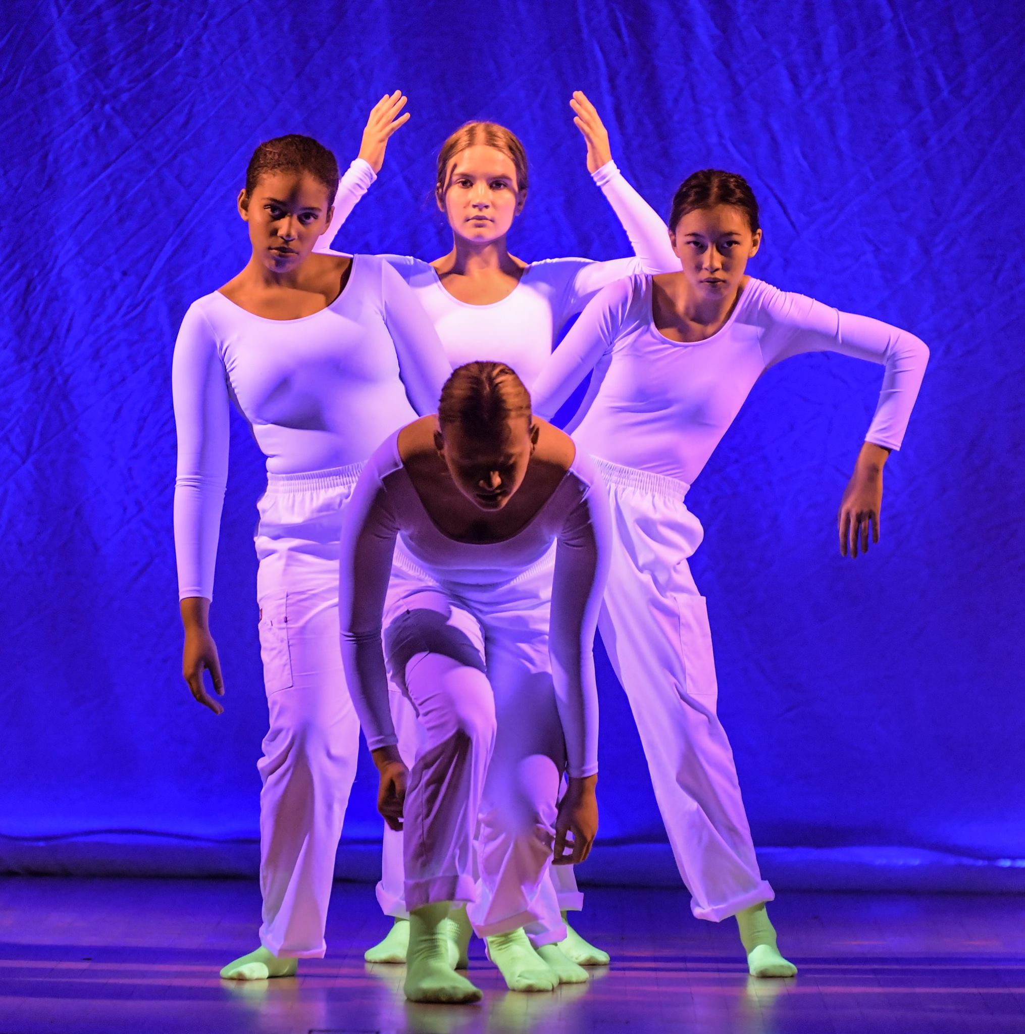 Four girls performing, all clad in white and bright green socks