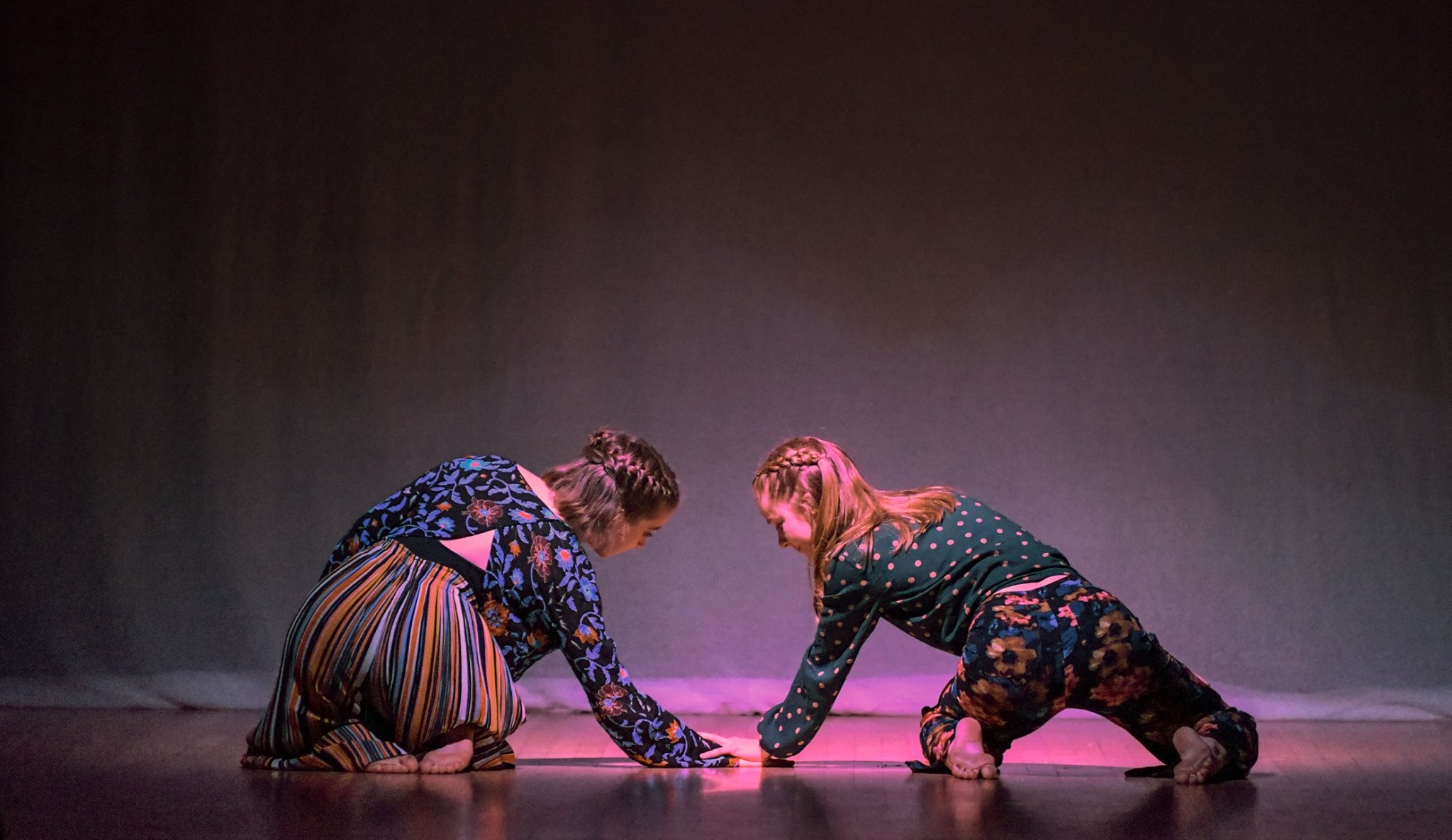 Two girls performing on the school's theatre the two of them dressed up in bright clothing