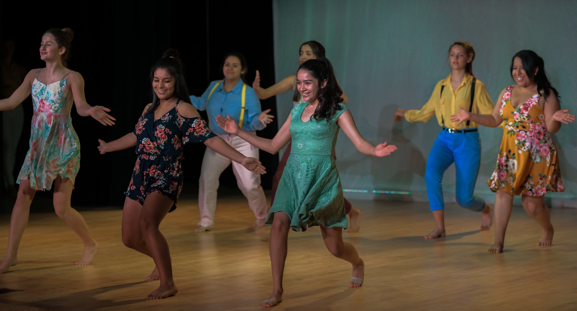 A choreographed dance being performed, the majority of girls dressed up in floral dresses
