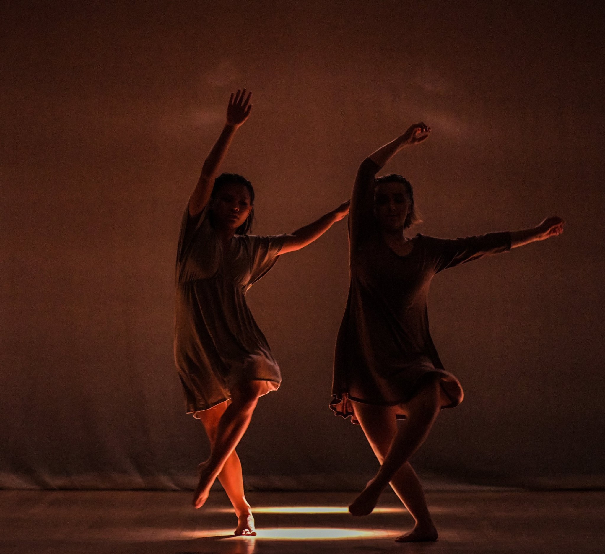 Two girls dancing and the lighting only illuminating the floor and their legs