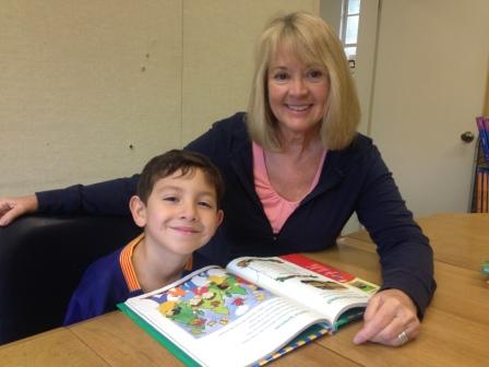 A photo of a teacher and a kid reading together a book