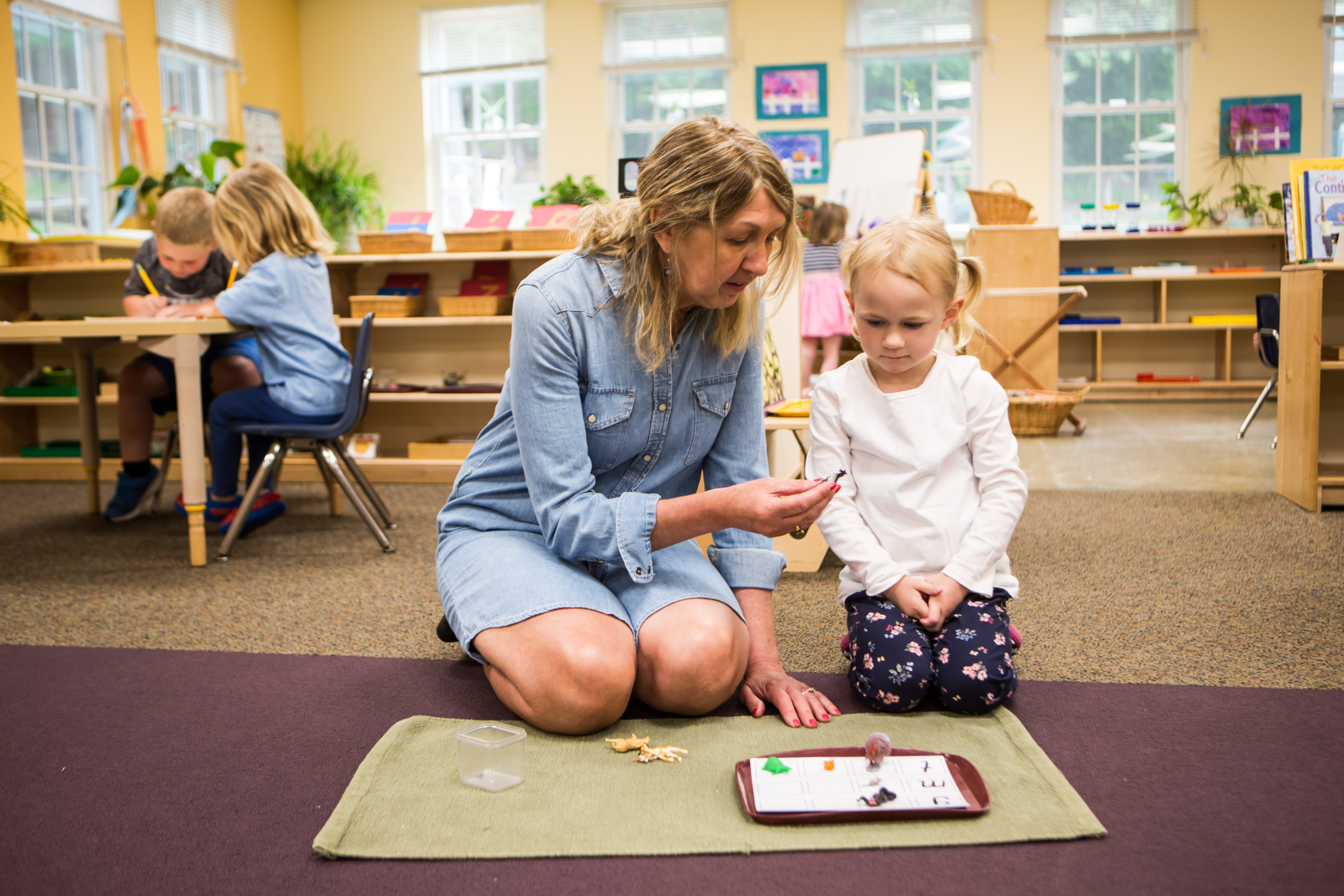 A photo of a teacher helping a student with a game.