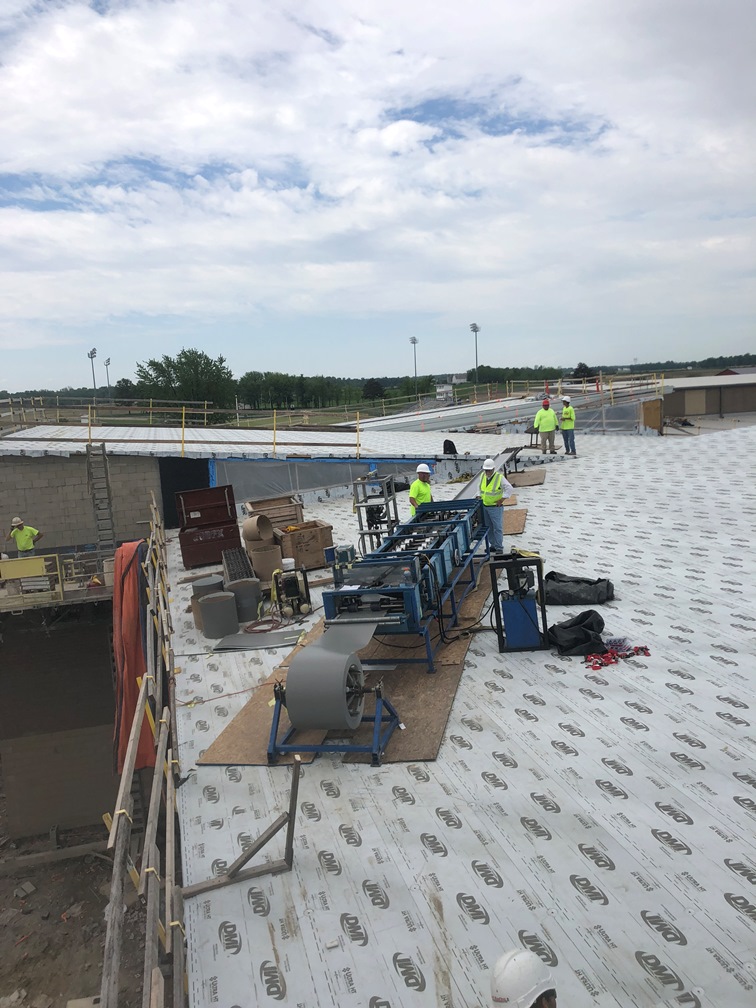 Photos of the Metal for the roof is being formed on a machine on the roof. There will not be any seams.