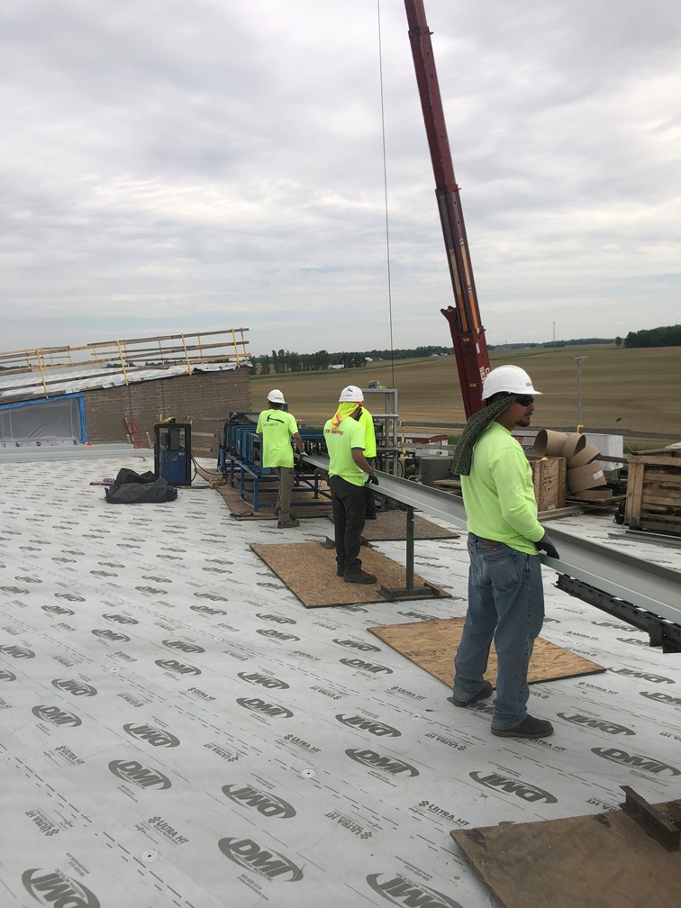 Photo of the Workers holding the roof metal so it does not bend.