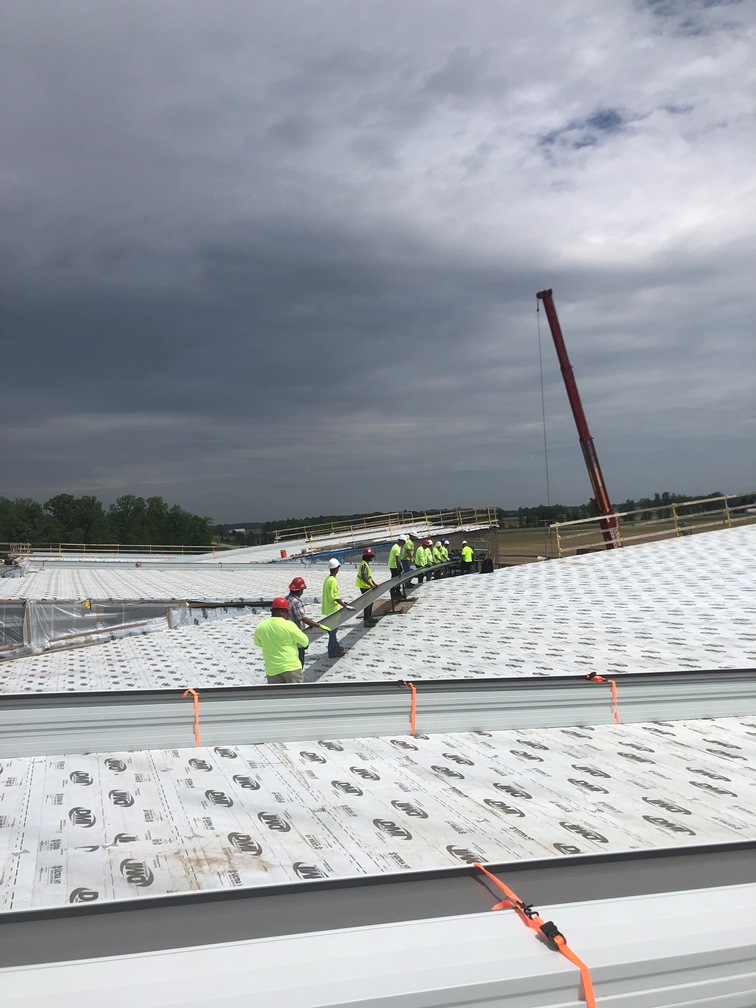 Photo of the Workers holding the roof metal.