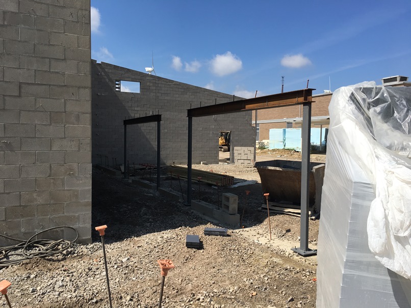 Photo of the entrance to the media center is between the steel columns. This is next to the new gym, and the old building is in the background.
