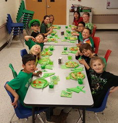Kids all lines up for their lunch and smiling at the camera