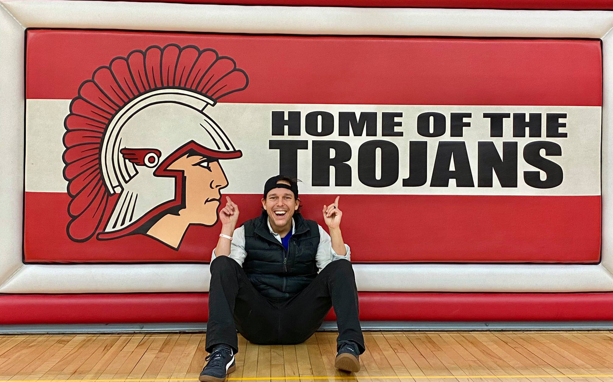 Joe Beckman posing in front of Home of the Trojans sign