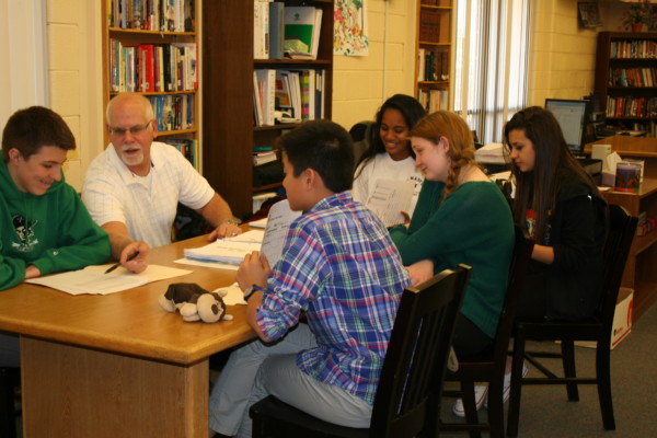 A group of students sitting down with a tutor in a library