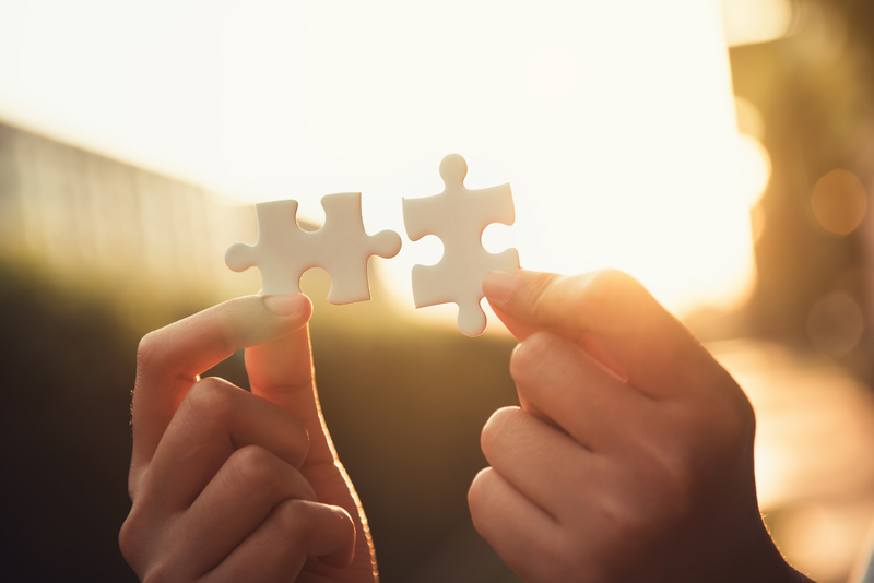 two hands connecting puzzle pieces