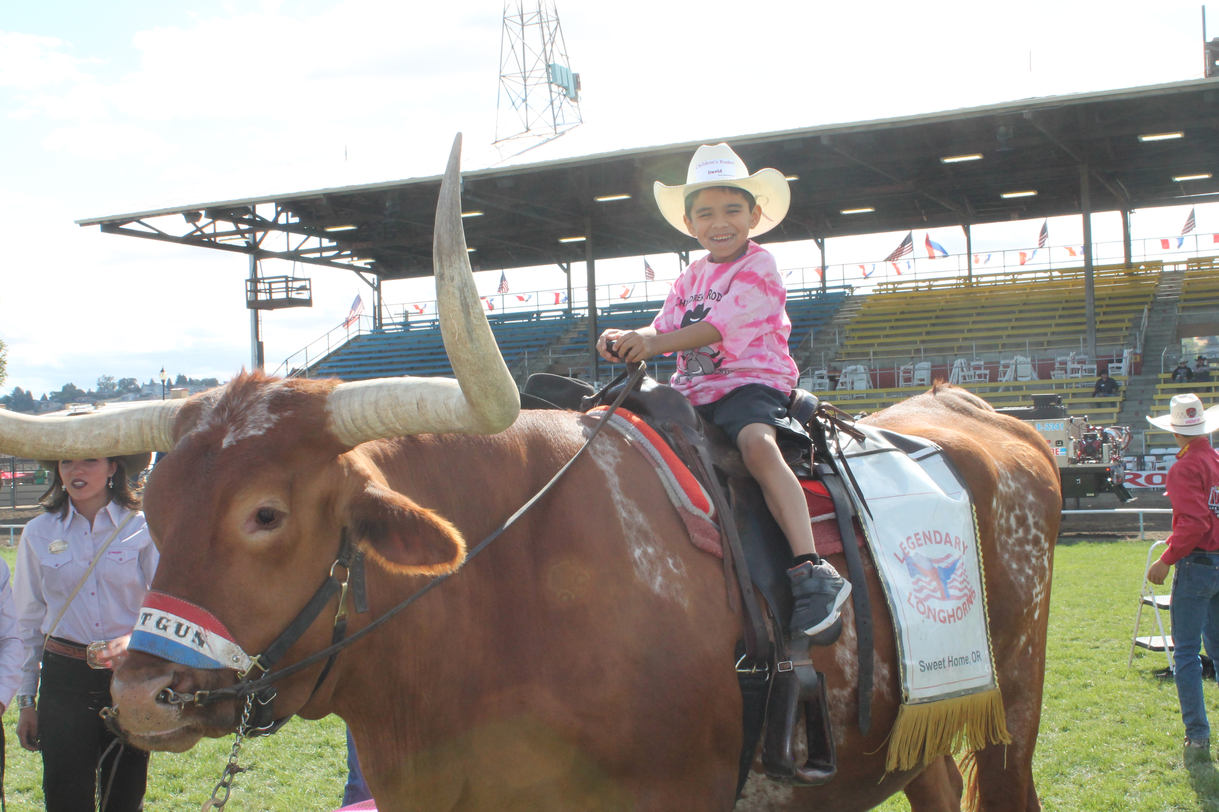 A photo of a kid riding a longhorn.