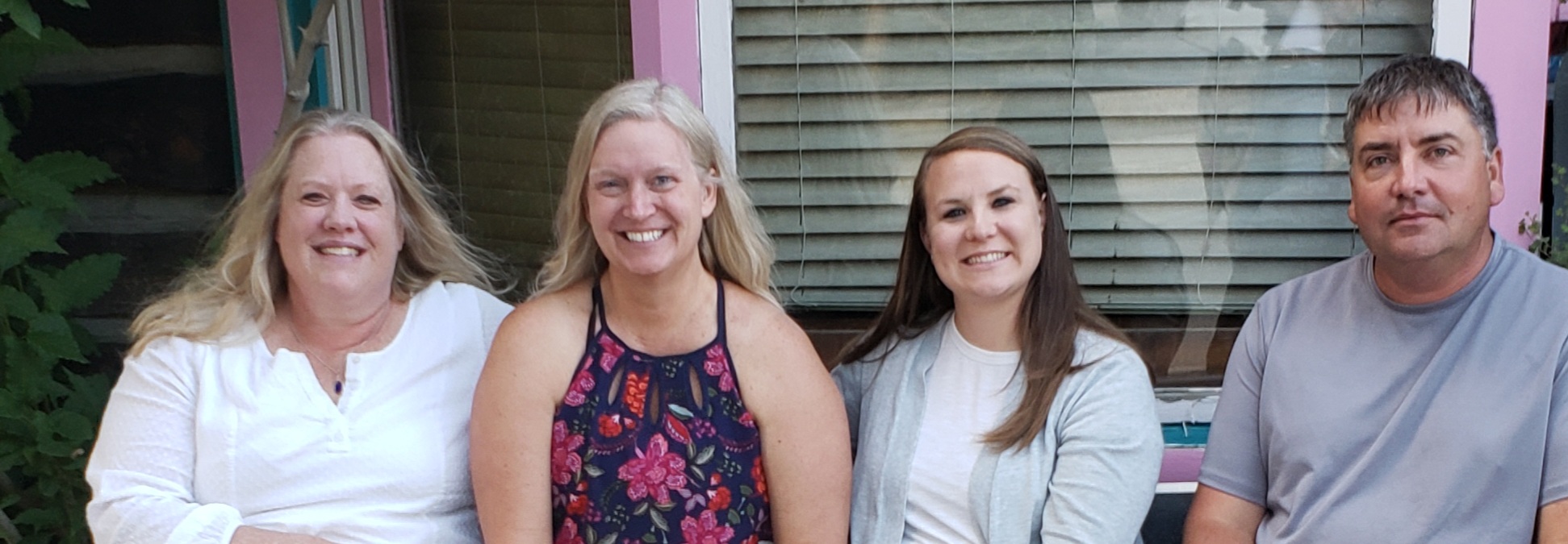 staff members standing outside building, smiling