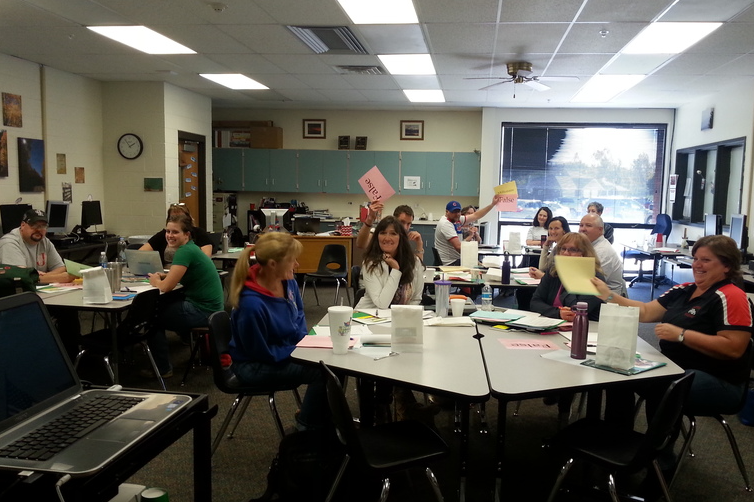 Small groups of teachers sit at tables