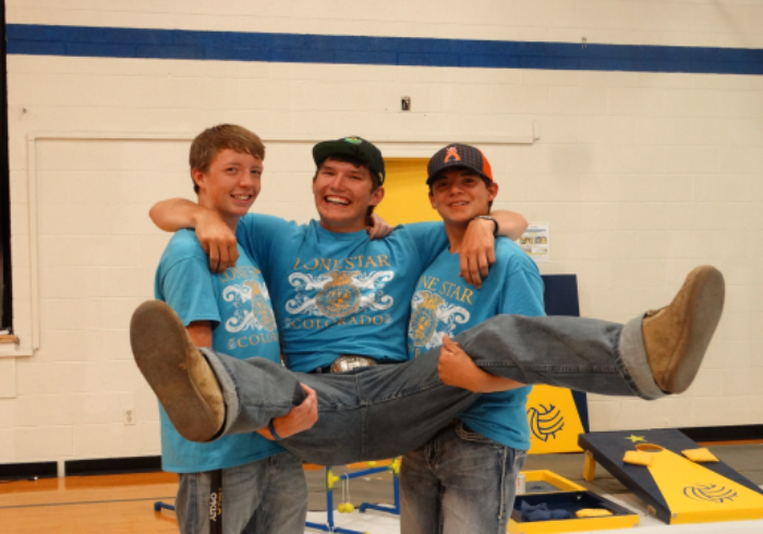 2 boys holding another boy up smiling