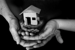 Black and white photo of hands holding a birdhouse