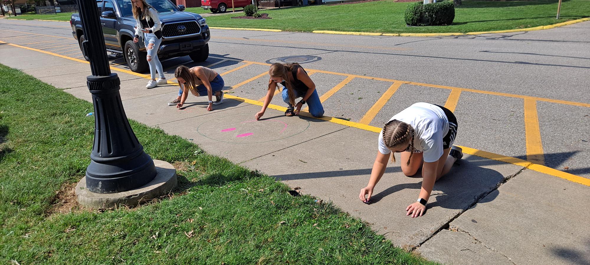 students drawing on sidewalk