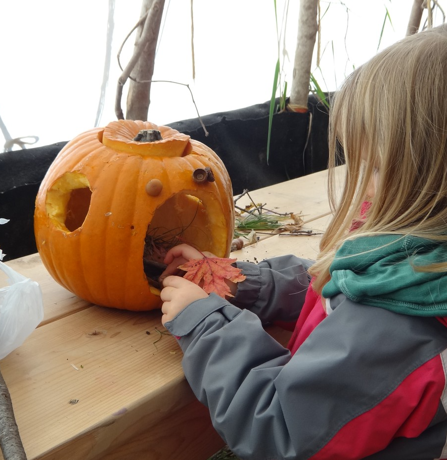 child crafting with a pumpkin