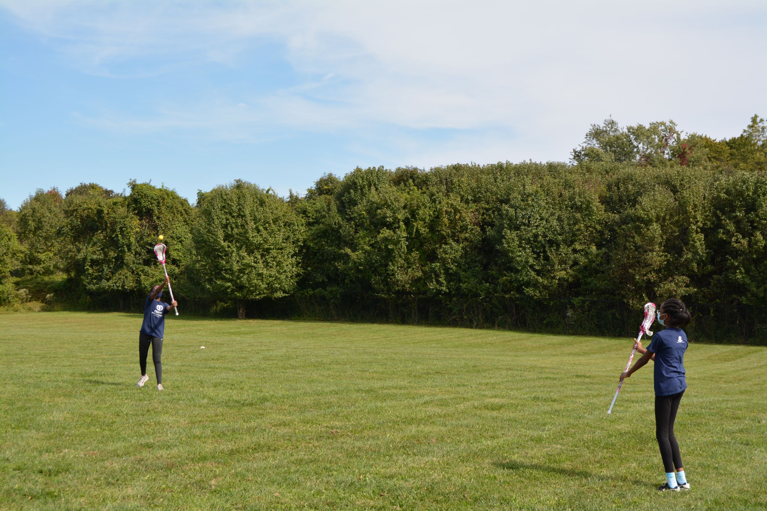 Two girls passing to each other in lacrosse
