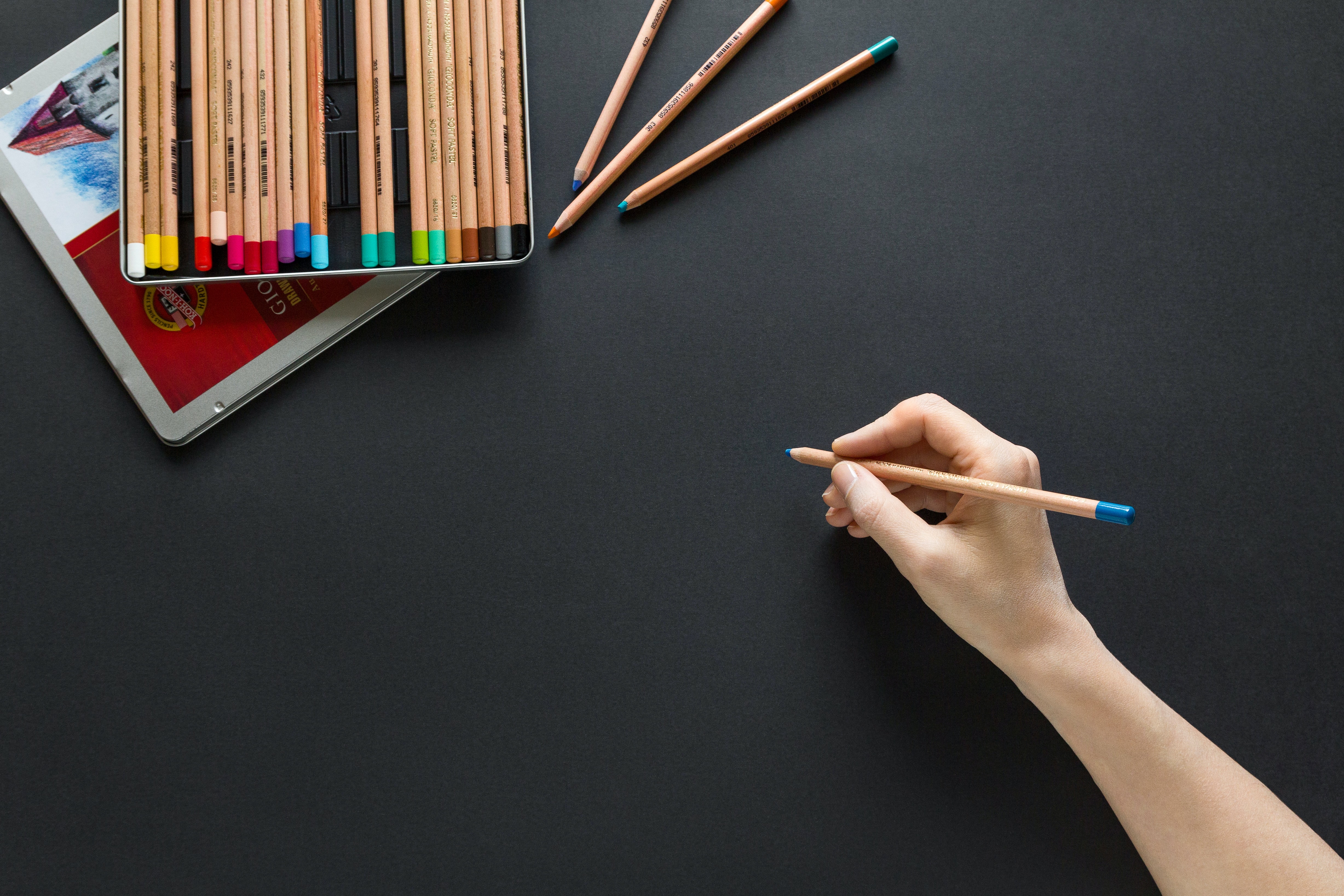 hand holding pencil with colored pencils