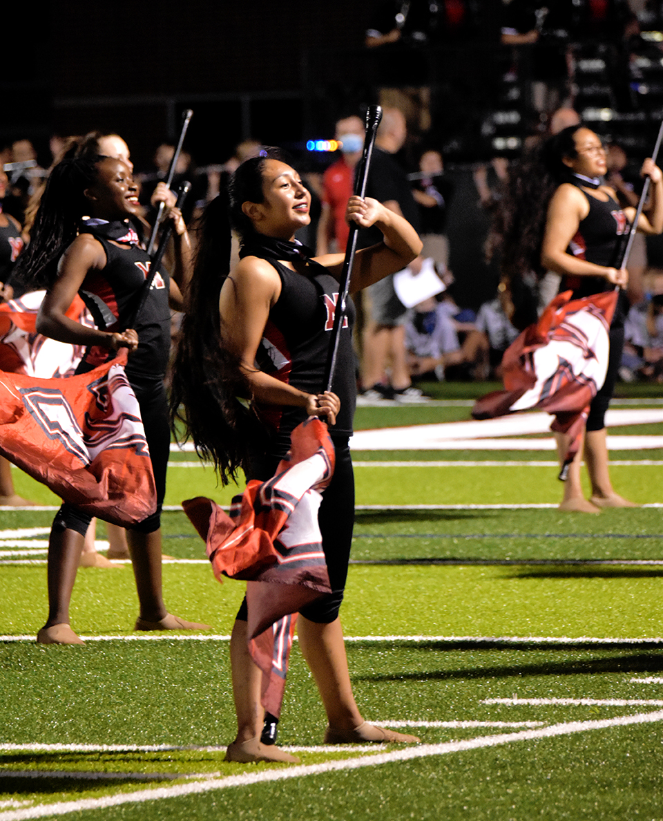 Colorguard student stands with flag during halftime performance