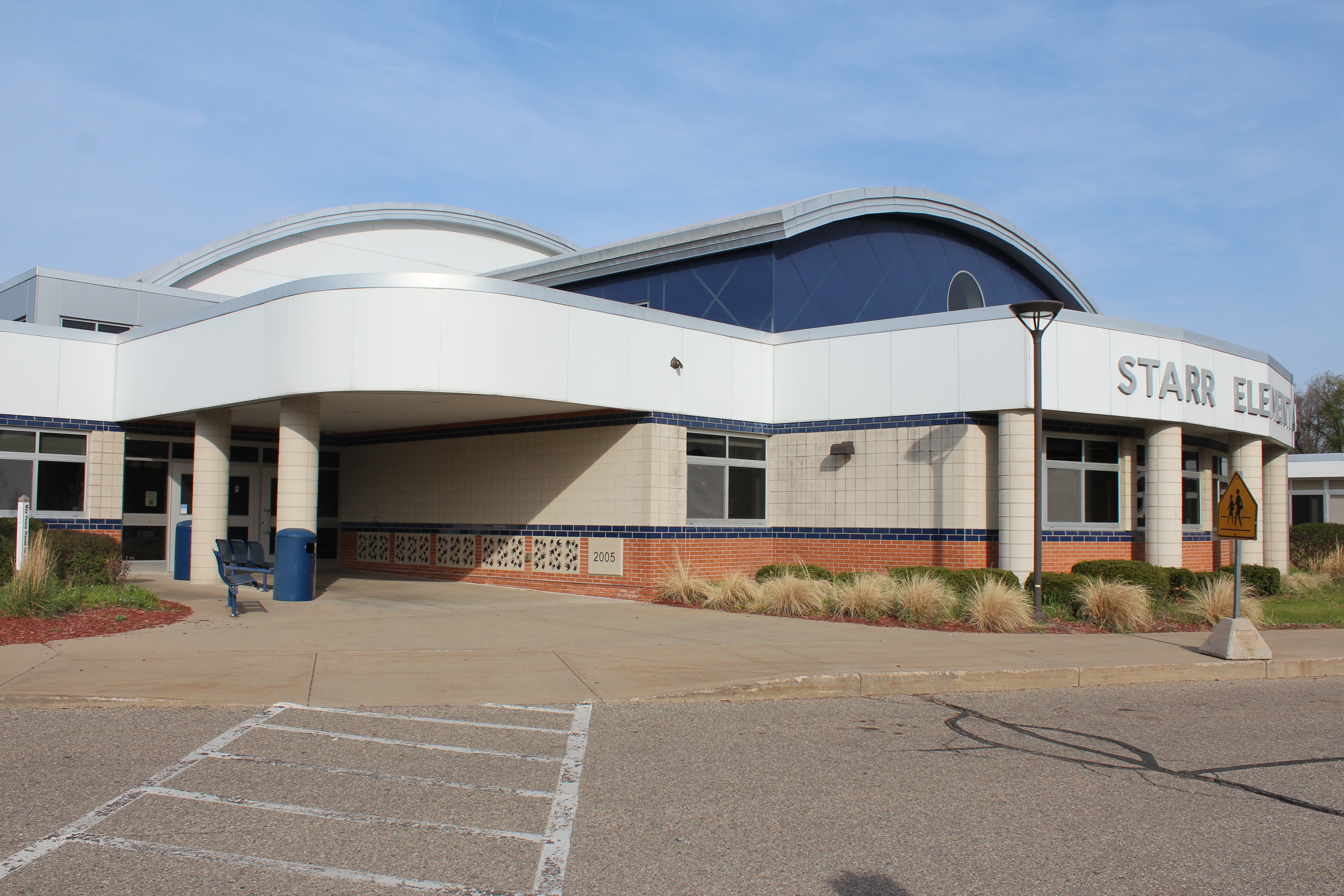 Exterior picture of Starr Elementary with walkway of entrance to building with students handprints along the wall