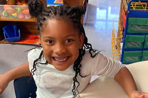 Student smiling at desk eating snacks