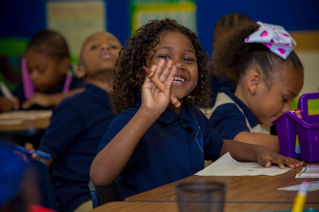 Happy young female student waving