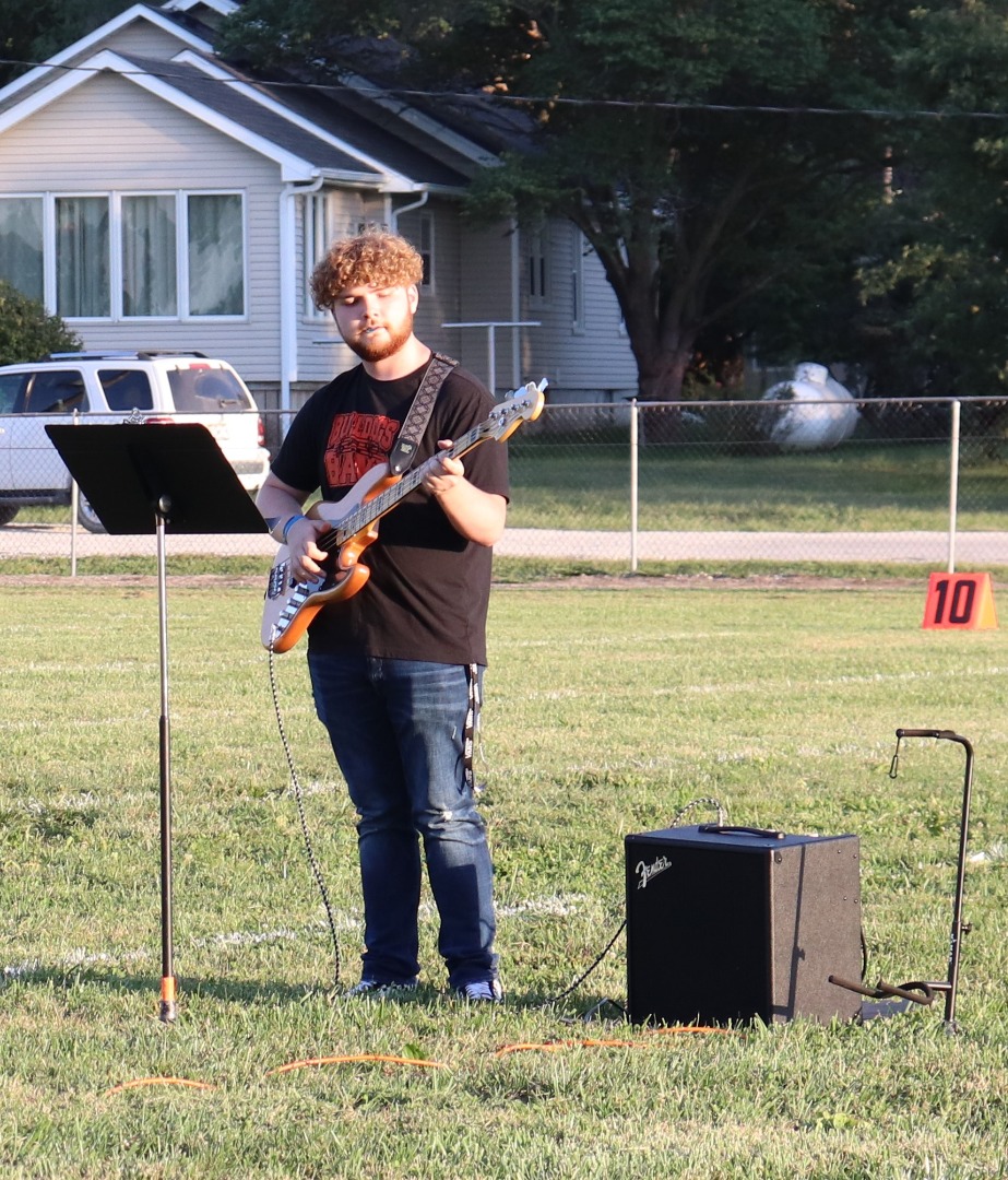 Student playing guitar on the football feild