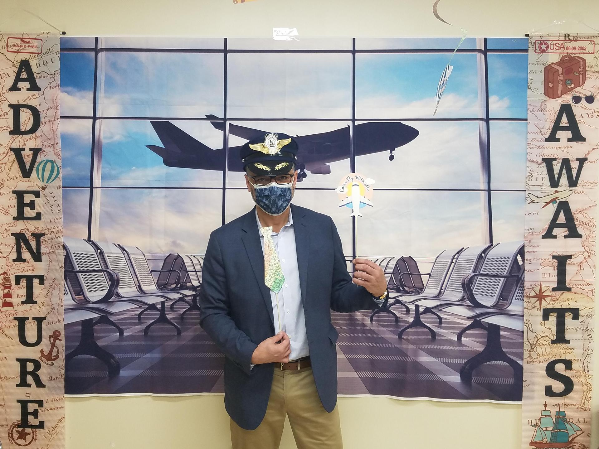 Man dressed as a piolet standing in front of an airport poster