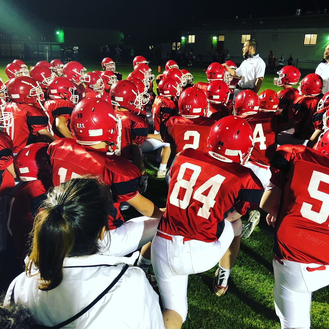 Football team huddling on knees by coach