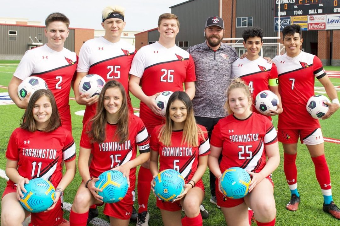 Senior players on soccer teams pose with ball
