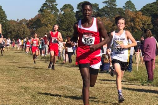 boy running towards finish line in cross country