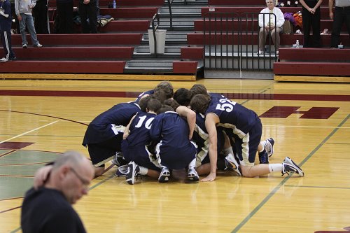 An image of the basketball team in a huddle in the middle of the basketball court